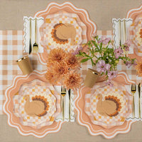 Long harvest table styled on the gingham runner with multiple turkey place settings and florals.