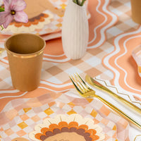 Place setting on the gingham runner with turkey plate, peach scalloped placemat, and gold flatware.