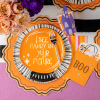 Overhead place setting with crystal ball plate on stripe rim plate beside orange BOO favor bag and florals.