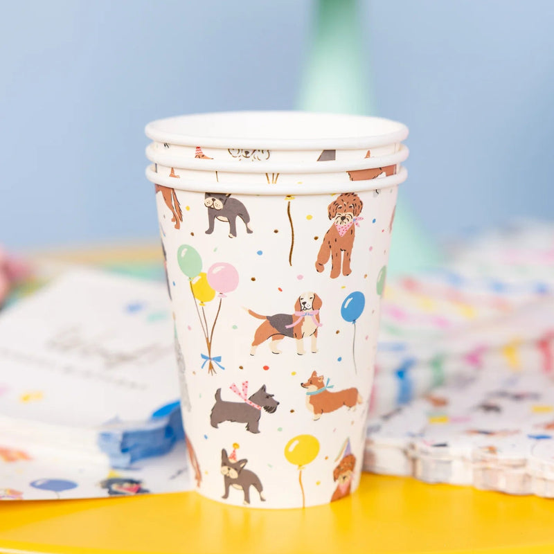 Close view of a single dog party cup on a yellow table showing balloons, confetti, and party dogs.