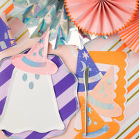 Tablescape with ghost plate, haunted house cup, and party fans with an orange scalloped guest towel layered under a hat napkin.