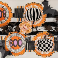 Overhead Halloween table with orange scalloped paper placemats layered under patterned plates and florals.