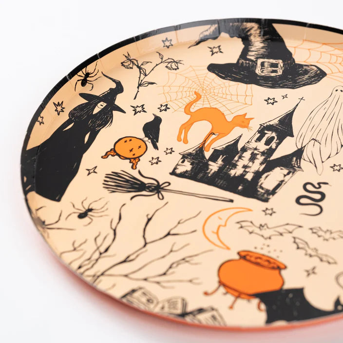 Close up of Halloween icon plate edge showing witch, broom, spiderweb, and castle on a peach orange background.