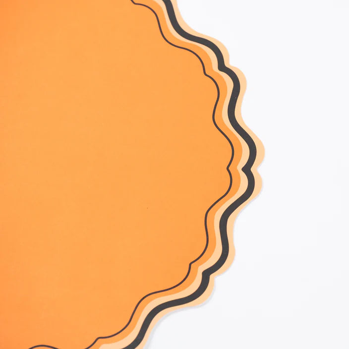 Close up of orange scalloped placemat showing layered black and peach border detail.