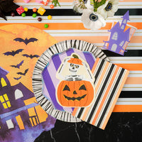 Overhead view of striped Halloween runner with haunted house placemat and layered plates.