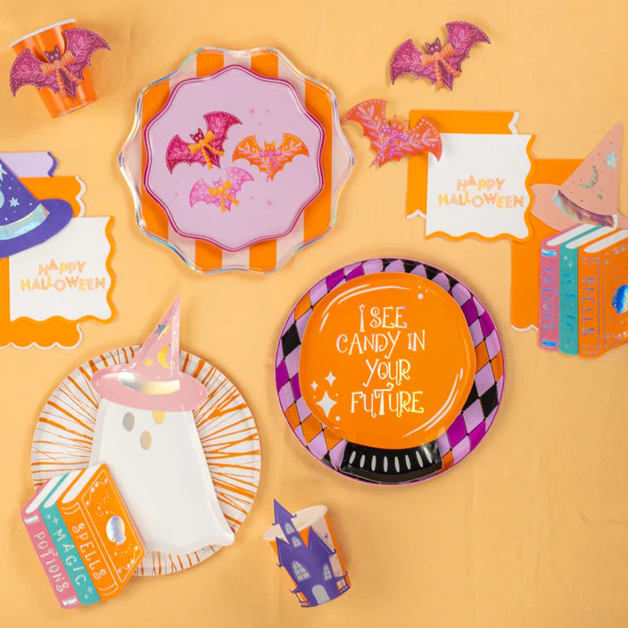 Party flat lay with plates and cups, Happy Halloween napkin styled on an orange background.