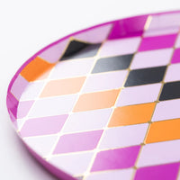 Macro detail of gold foiled grid between colored diamonds on the Halloween plate rim.