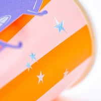 Macro of pink and orange striped Halloween cup with silver stars.