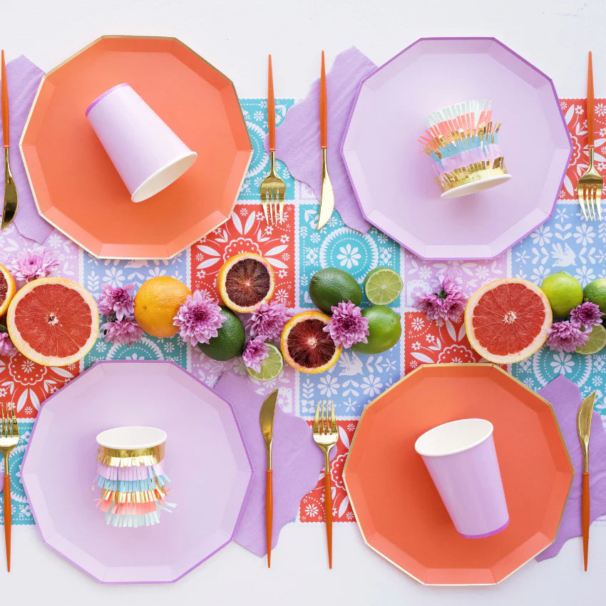 Colorful tablescape with lilac dinner plate layered with citrus and florals, styled with purple paper napkins