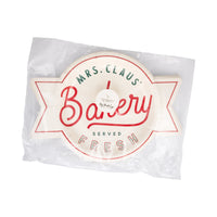 Front view of packaged “Mrs. Claus’ Bakery” shaped dessert plate in cream with red and green lettering