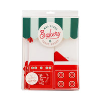 Front packaging of red oven Christmas cookie boxes labeled Mrs. Claus’ Bakery