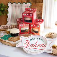 Cozy kitchen setup showing oven treat boxes beside “Mrs. Claus’ Bakery” shaped plate for serving Christmas cookies