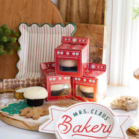 Holiday baking scene with oven treat boxes beside square scalloped Christmas paper plates