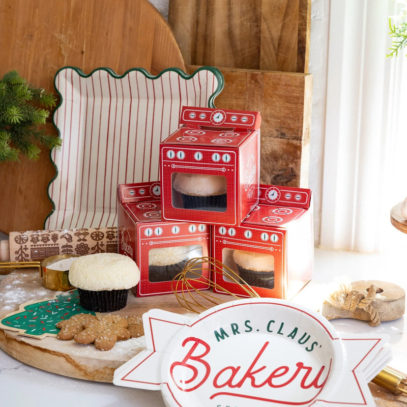 Holiday baking scene with oven treat boxes beside square scalloped Christmas paper plates