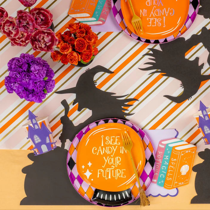 Witch runner tablescape with harlequin plate and an orange quote plate styled beside a spell book napkin.
