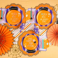 Overhead table with multiple place settings and fans featuring orange plates and mystical books cocktail napkins.