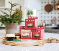 Trio of red oven Christmas treat boxes with clear windows on kitchen counter