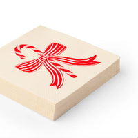 Stack of cream cocktail napkins with red candy cane bow for candy cane Christmas parties