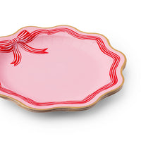 Close-up of pink plate with red peppermint bow and gold scalloped rim large red plates