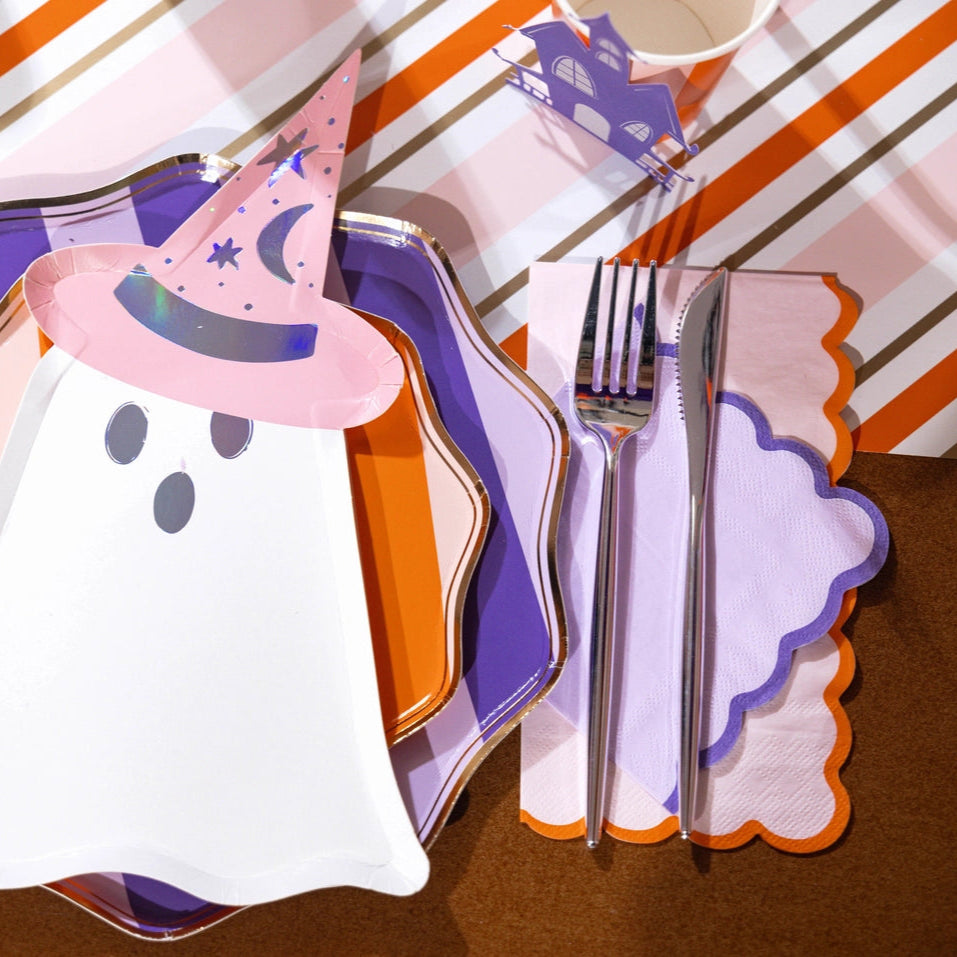 Ghost plate layered over striped dinner plates with lilac and orange scalloped cocktail napkins beside the flatware.