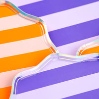 Iridescent rim detail of pink, orange, and purple striped scalloped dessert plates.