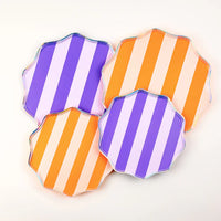 Set of four striped dinner plates in purple and orange arranged together.