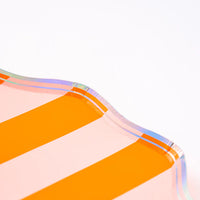 Corner closeup of orange and blush striped dessert plate showing scalloped edge and iridescent trim.