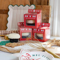 Holiday baking scene with oven treat boxes and green tree cookie napkin on board
