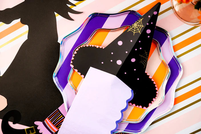Detail of witch’s hat napkin holder with lilac guest towel tucked through the slit on layered purple and orange plates.