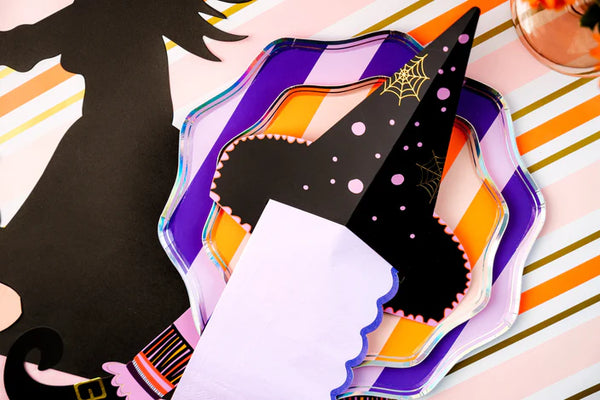Detail of witch’s hat napkin holder with lilac guest towel tucked through the slit on layered purple and orange plates.
