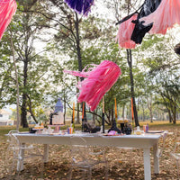 Outdoor Halloween table with tassel garlands, striped runner, and place settings styled with witch’s hat napkin holders.