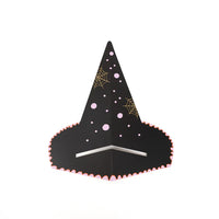 Witch’s hat napkin holder styled on layered striped plates with scalloped edge napkin tucked underneath.