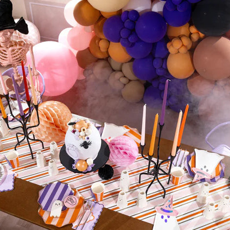 Halloween tablescape with balloon garland and place settings featuring witch hat napkins and ghost plates.