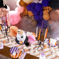 Halloween tablescape with balloon garland and place settings featuring witch hat napkins and ghost plates.
