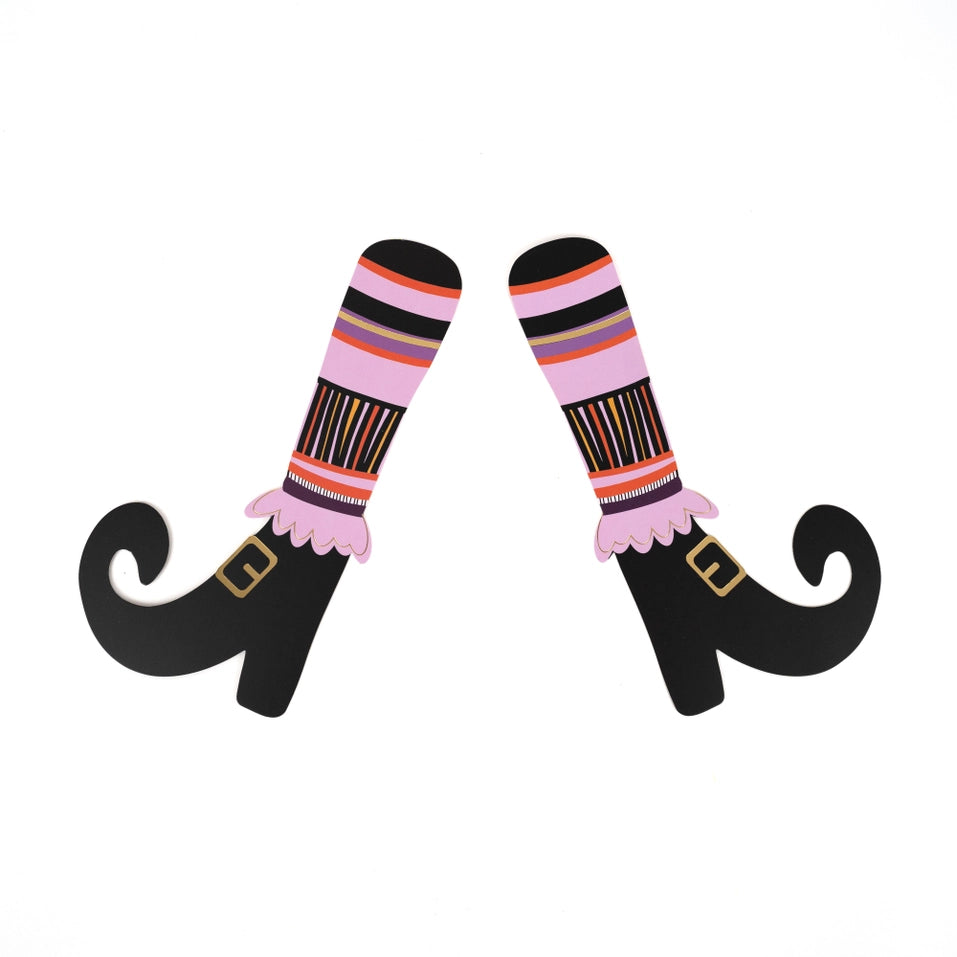 Single pair of paper witch’s legs with striped socks and buckled shoes on a white background.