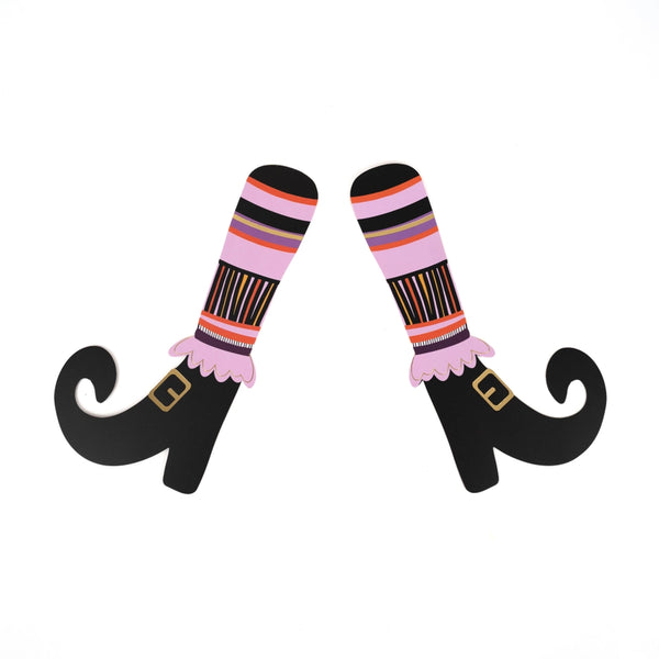 Single pair of paper witch’s legs with striped socks and buckled shoes on a white background.