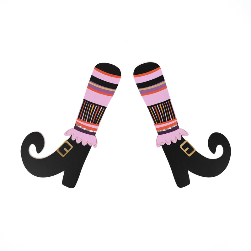 Single pair of paper witch’s legs with striped socks and buckled shoes on a white background.