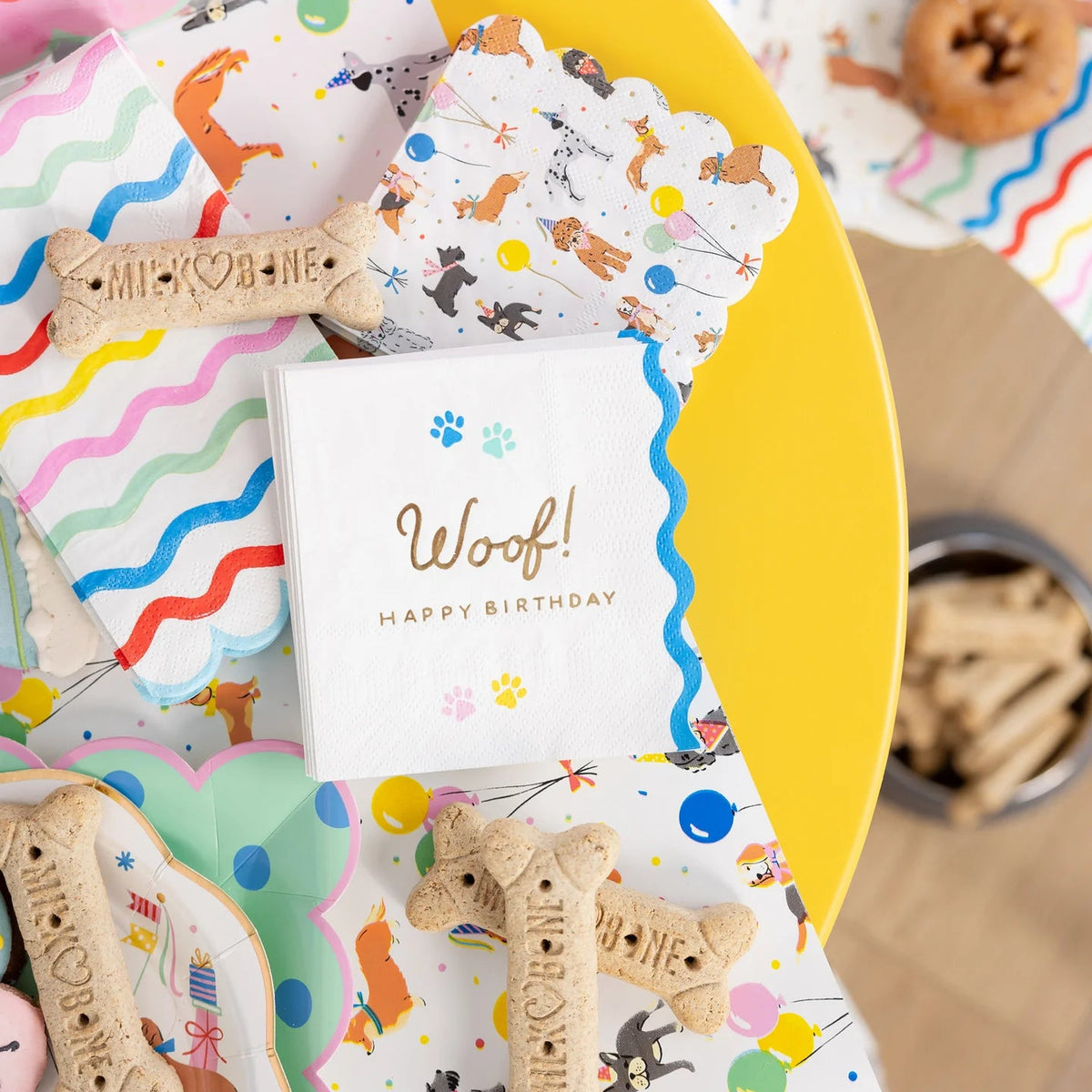 Yellow table setup with patterned napkins, plates, and Woof Happy Birthday napkin.