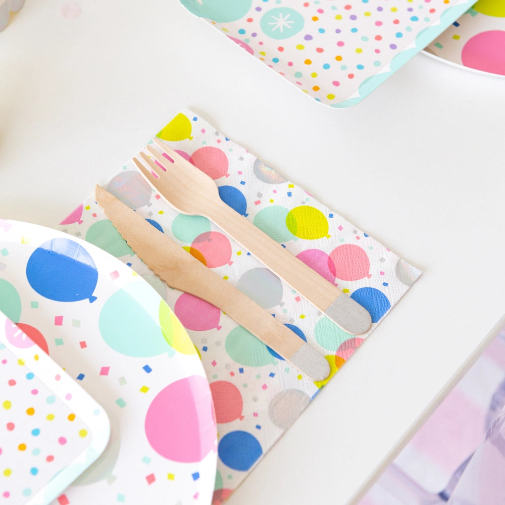 Close-up of wooden fork and knife resting on multicolor balloon lunch napkin with subtle holographic foil balloons	