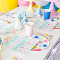 Side view of balloon plate and coordinating napkin on white table with party hats and pastel cups—ideal for adult or kids’ birthdays	