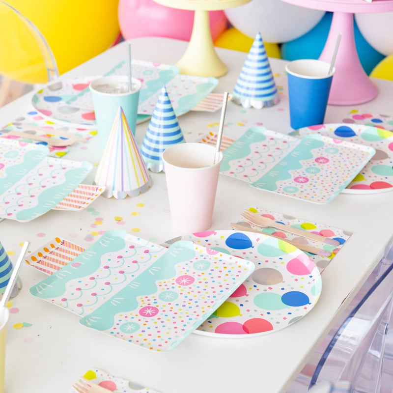 Styled party table with cake-shaped plates, balloon plates, pastel cups and hats, perfect for versatile birthday party ideas