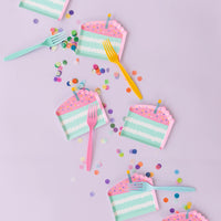 Overhead purple backdrop showing multiple cake-slice canapé plates with confetti and pastel forks—ideal for appetizer bars