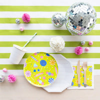 Styled table with candy napkin under wooden utensils beside yellow candy plate, disco balls, and striped runner