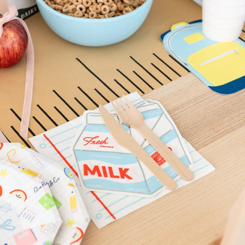 Milk-carton napkin layered over notebook napkin in back-to-school breakfast setup	