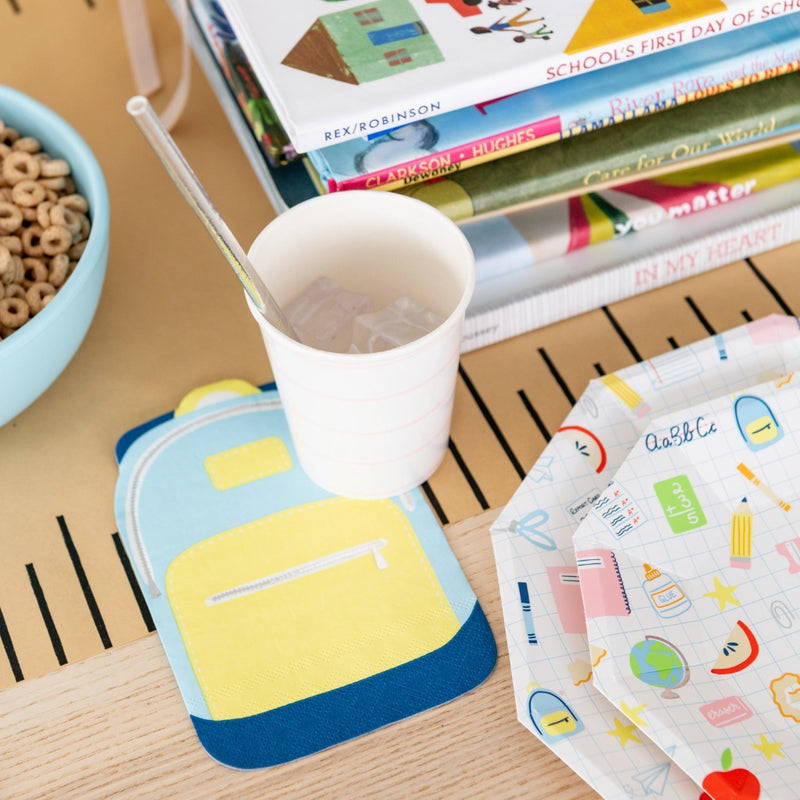 Lifestyle scene: backpack napkin coaster, notebook-lined cup, and a stack of Smarty Pants small plates ready for multi-age back to school breakfast