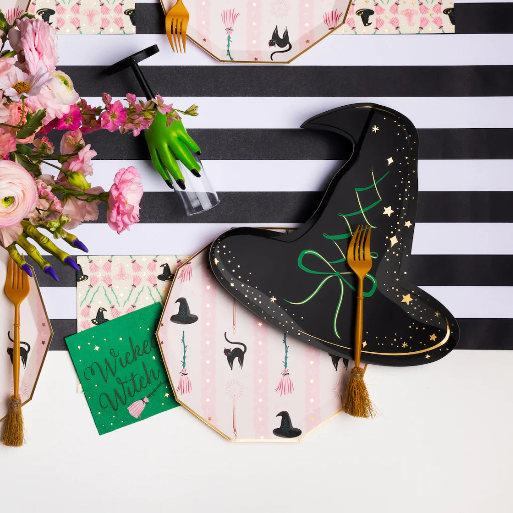Close table view with black witch hat plates, green hand cup, floral décor, stylish halloween paper plates