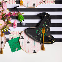 Close table view with black witch hat plates, green hand cup, floral décor, stylish halloween paper plates