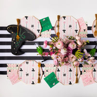 Overhead table styled with black and pink witch hat plates, striped runner, chic halloween paper plates setup