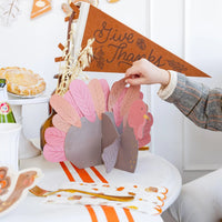 Child adding a feather to the chipboard turkey at the table