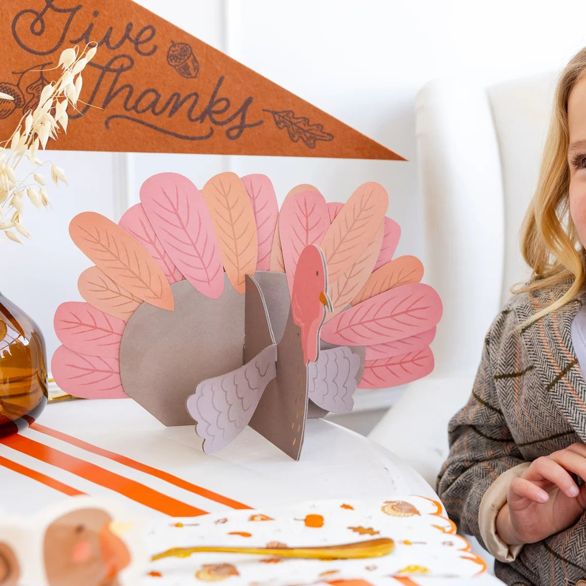 Child smiling next to assembled turkey with Give Thanks pennant